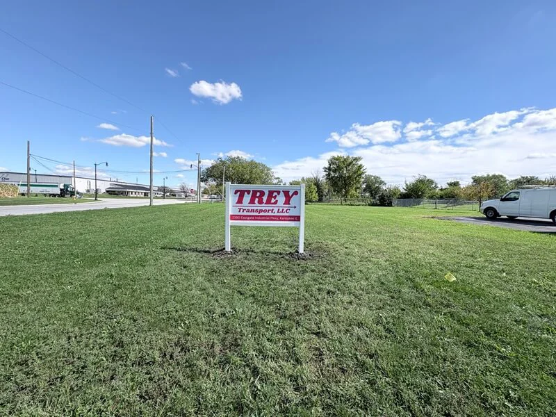 An image of a white and red exterior post and panel sign that reads, "Trey".